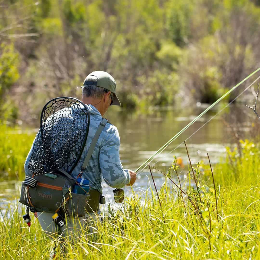 816332015694 EHLP-P Fishpond Elkhorn Lumbar Pack Pebble New Fishpond Waist Pack Front Walking Through Grass Near A River Head Down