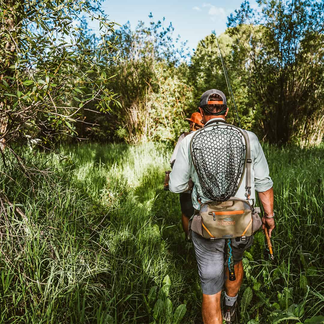 816332015694 EHLP-P Fishpond Elkhorn Lumbar Pack Pebble New Fishpond Waist Pack Front Walking along river brush
