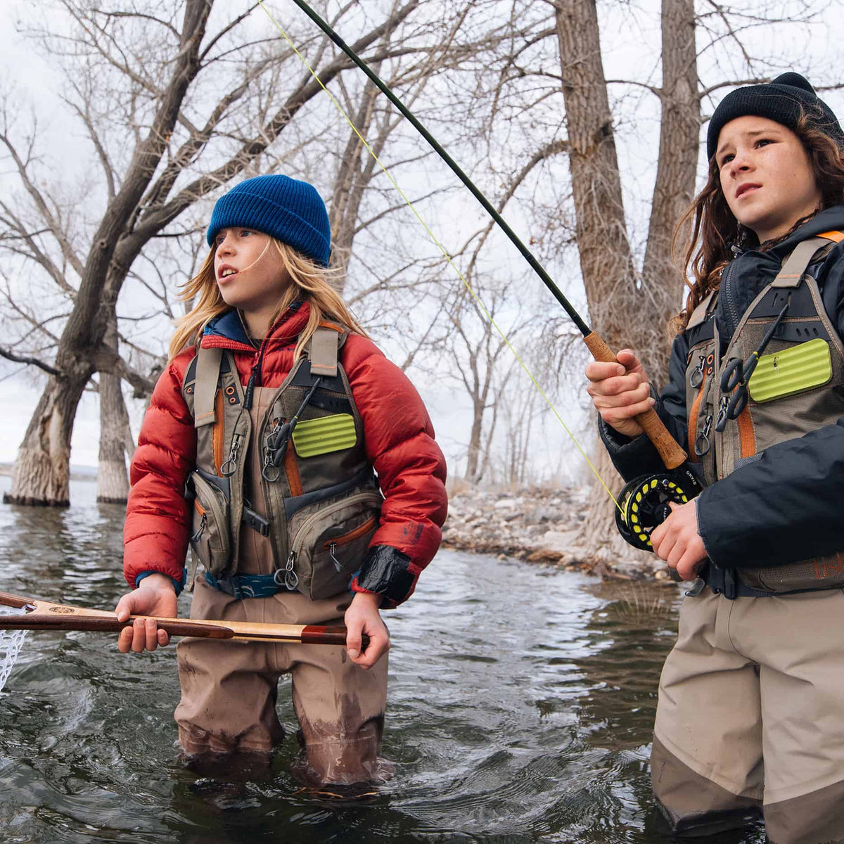 Two children fishing with their Fishpond Tenderfoot Kids Fishing Vests on