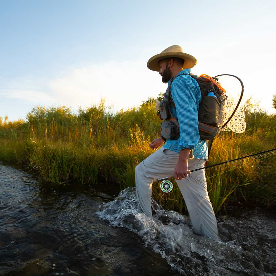 RLTP 816332014963 Fishpond Ridgeline Tech Pack Fly Fishing Vest and Travel Backpack Walking up stream shwoing water bottle pocket