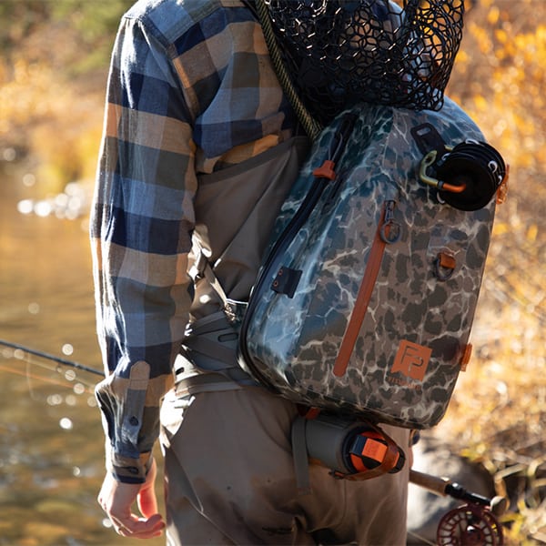 THS-ERC 816332015090 fishpond thunderhead waterproof fly fishing sling pack eco riverbed camo front on water