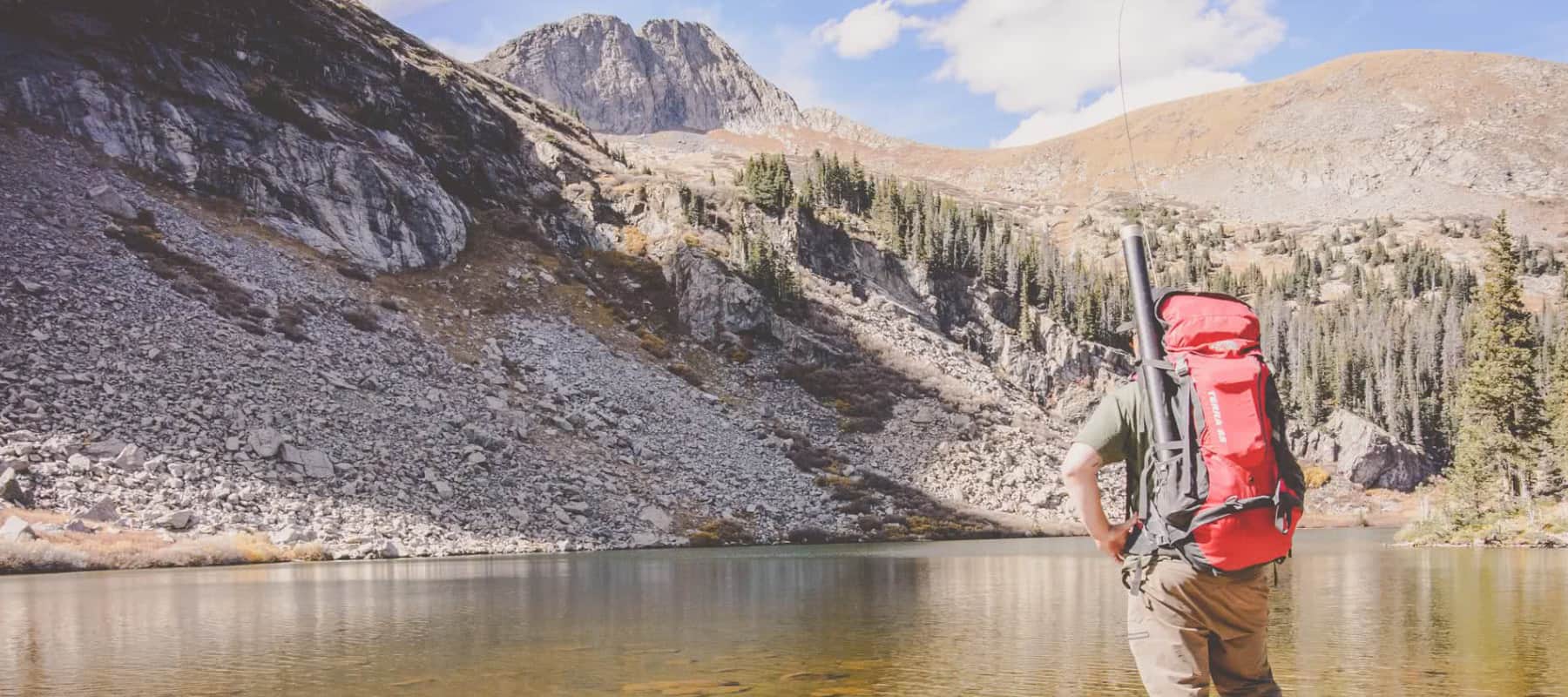 A man looks over the waters and contemplates fishing an alpine lake in Colorado